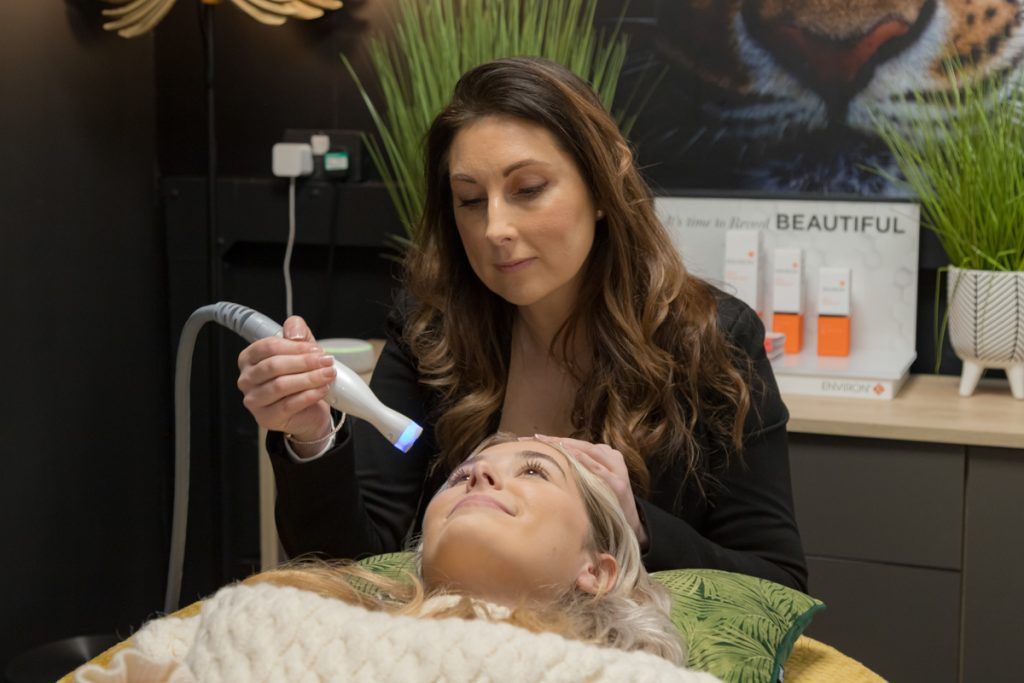 Female beauty therapist performing treatment on female client