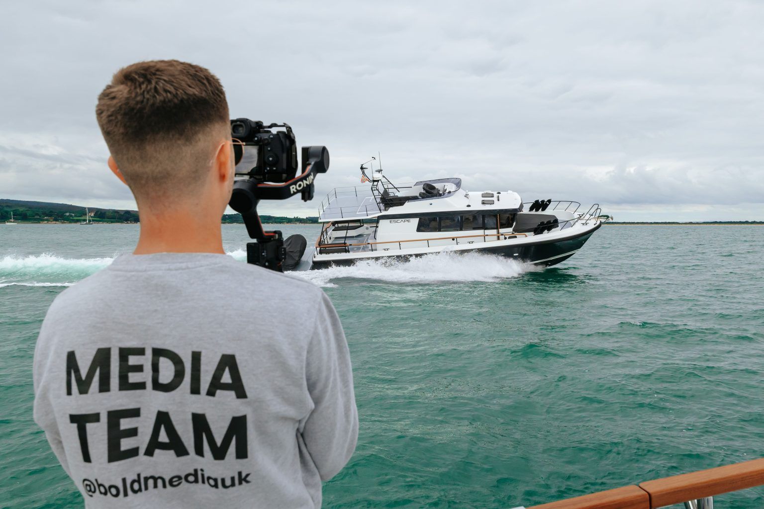 Male filming boat on the open water