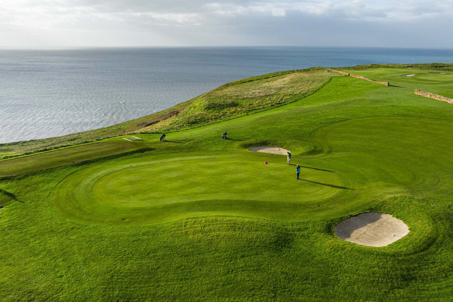 Green on golf course with sea in background