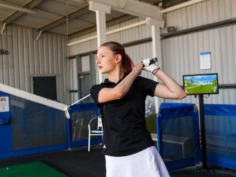 Young female golfer posing after taking a swing