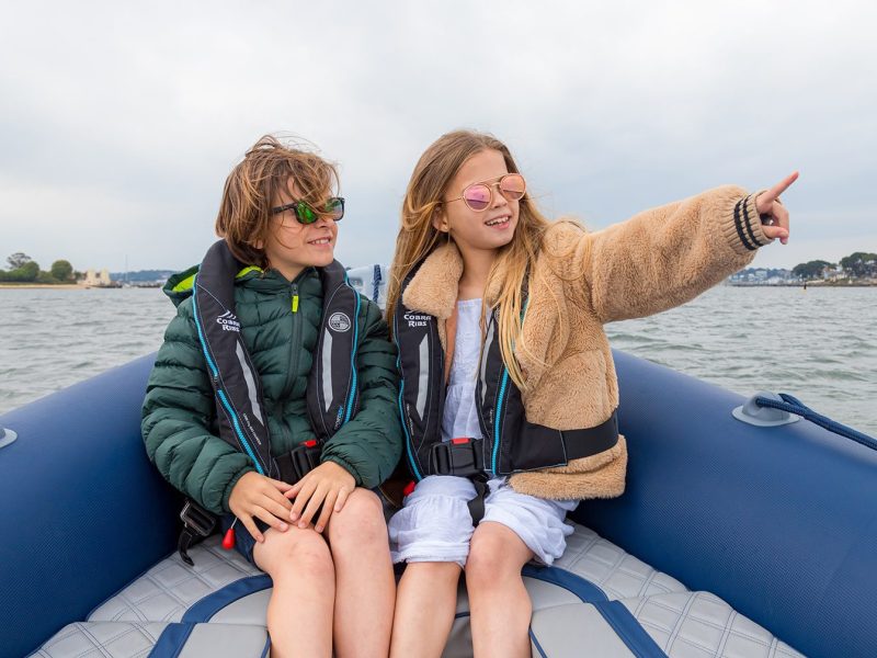 Two young children smiling on a boat at sea
