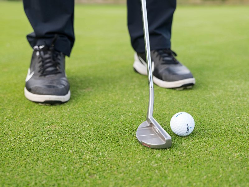 Golf ball and putter on green