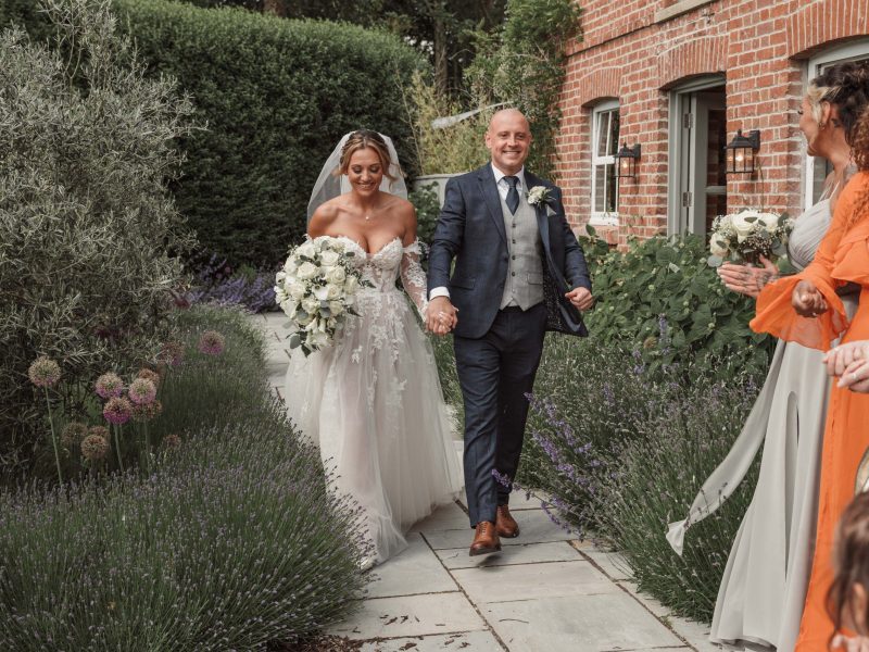Bride and groom walking down flower lined path after wedding