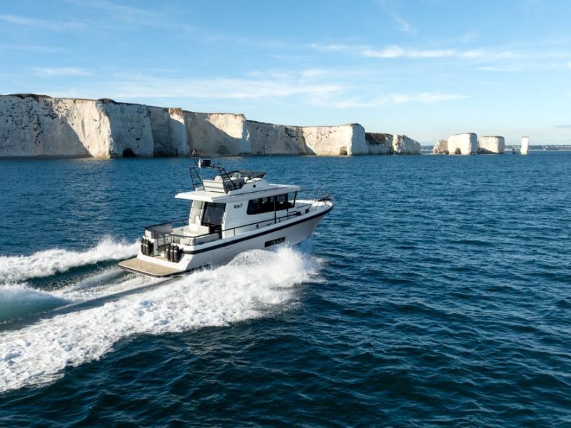 Boat traveling on water with cliffs behind