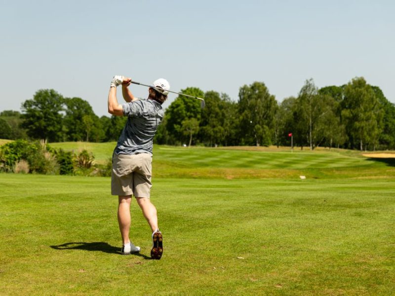Male golfer posing after taking a swing on a golf course